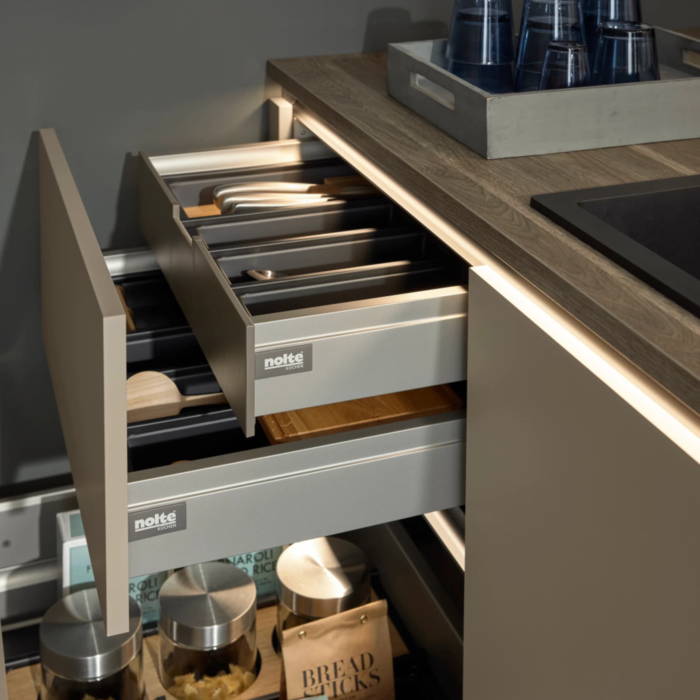Modern kitchen with lit drawers and wood countertop showcasing Nolte Kitchen design.