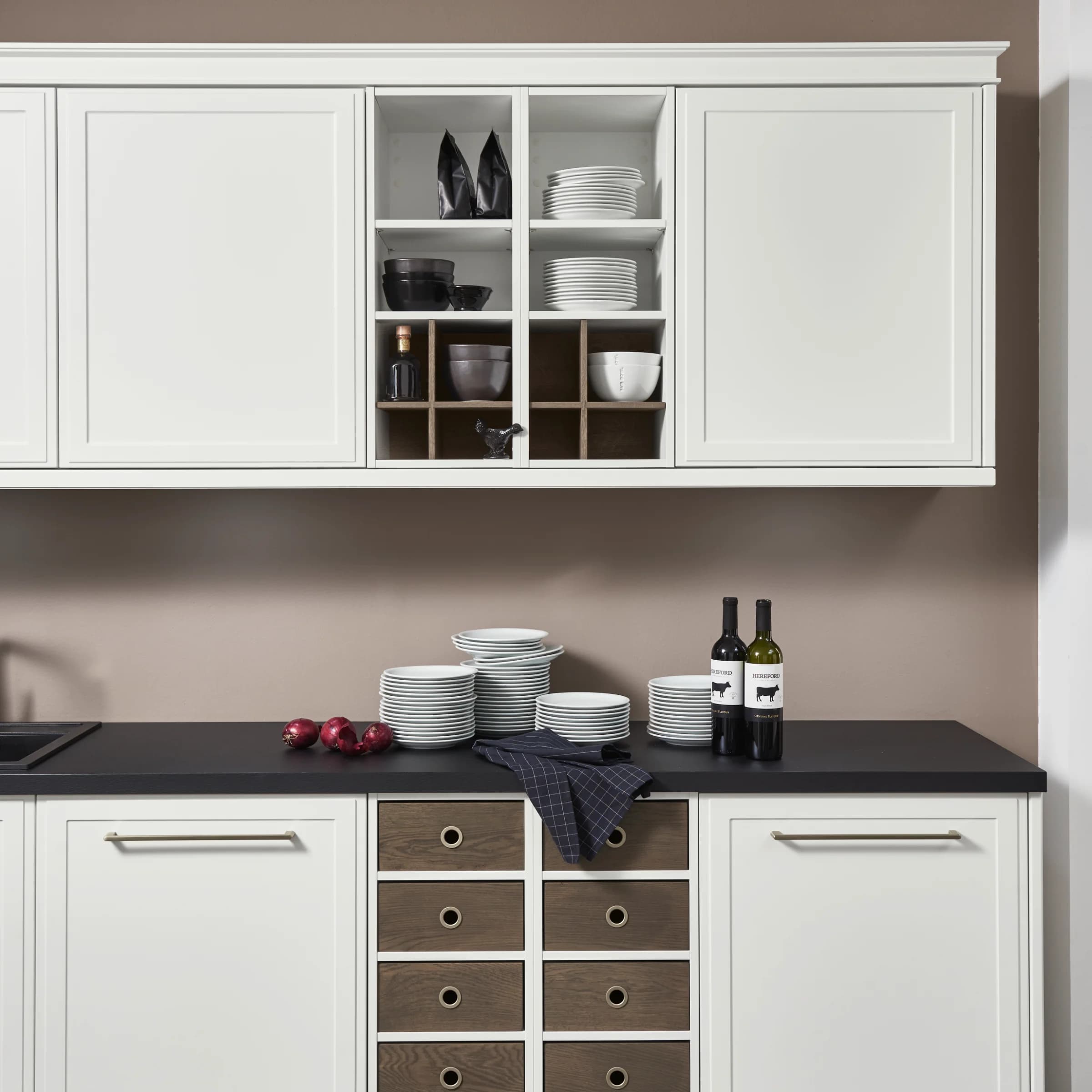A modern kitchen with white cabinets and a dark countertop, presented by Nolte Kitchen.