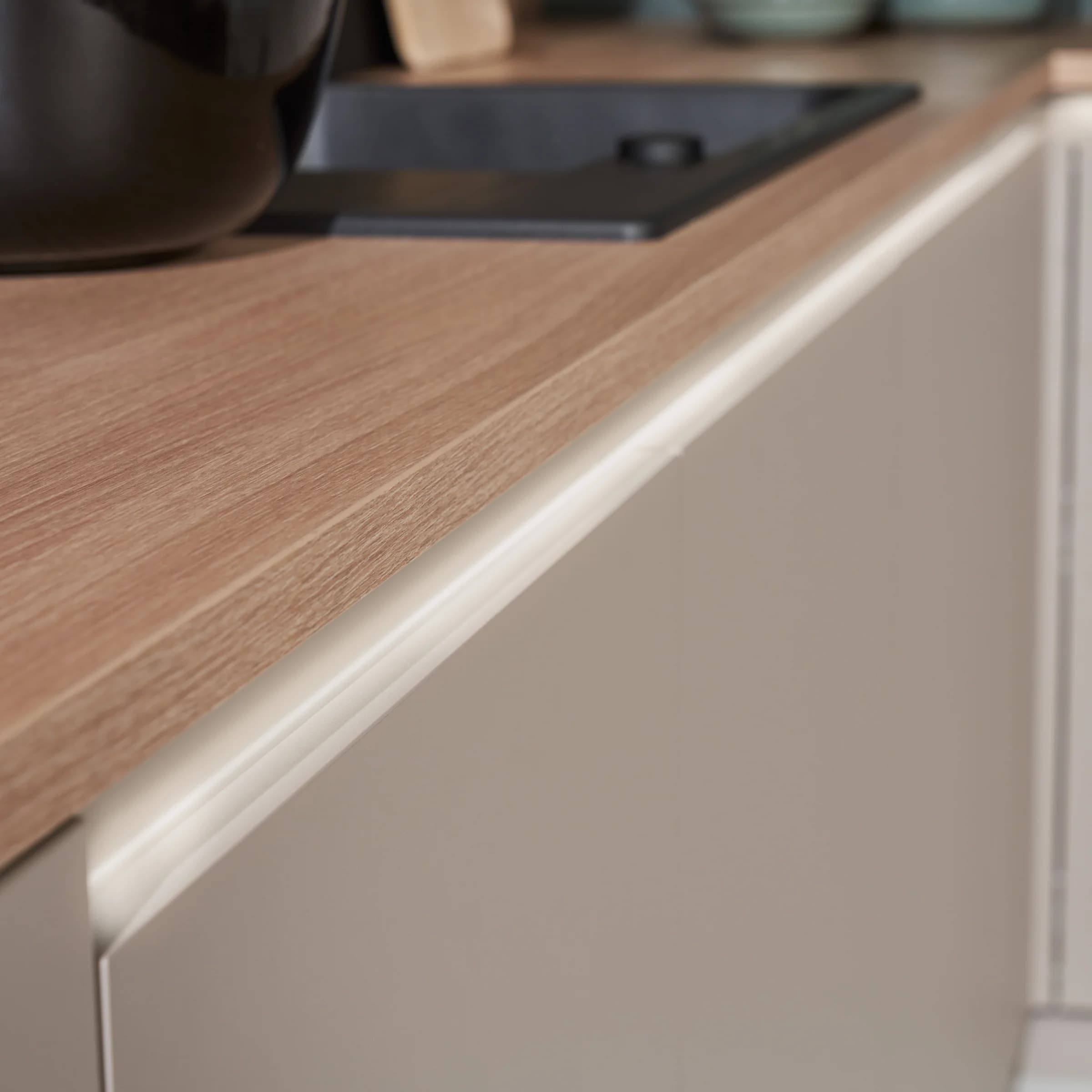 A modern kitchen with a wooden countertop and light cabinets by Nolte Kitchen.
