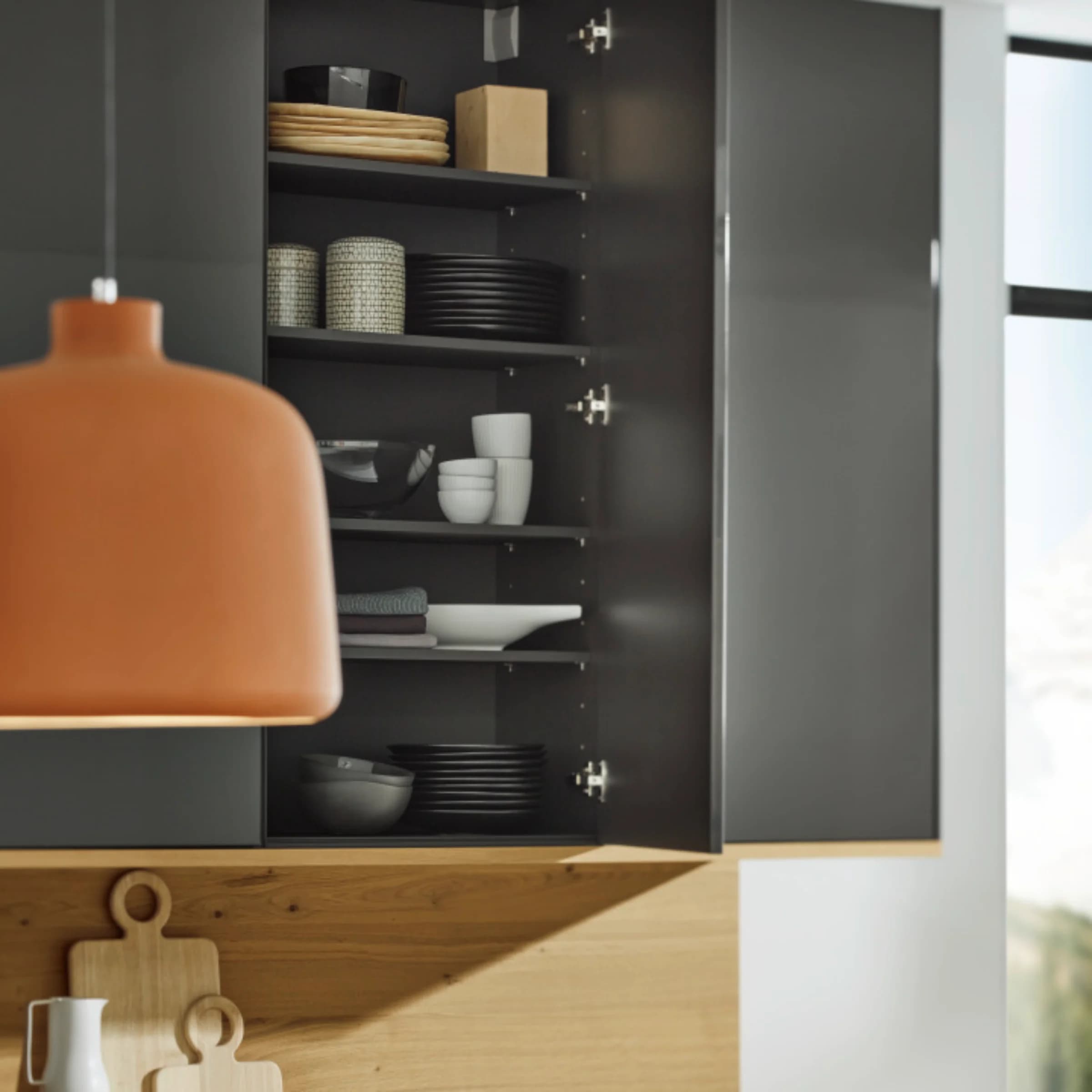 A modern kitchen with an open cabinet displaying dishes and wooden accessories, Nolte Kitchen.