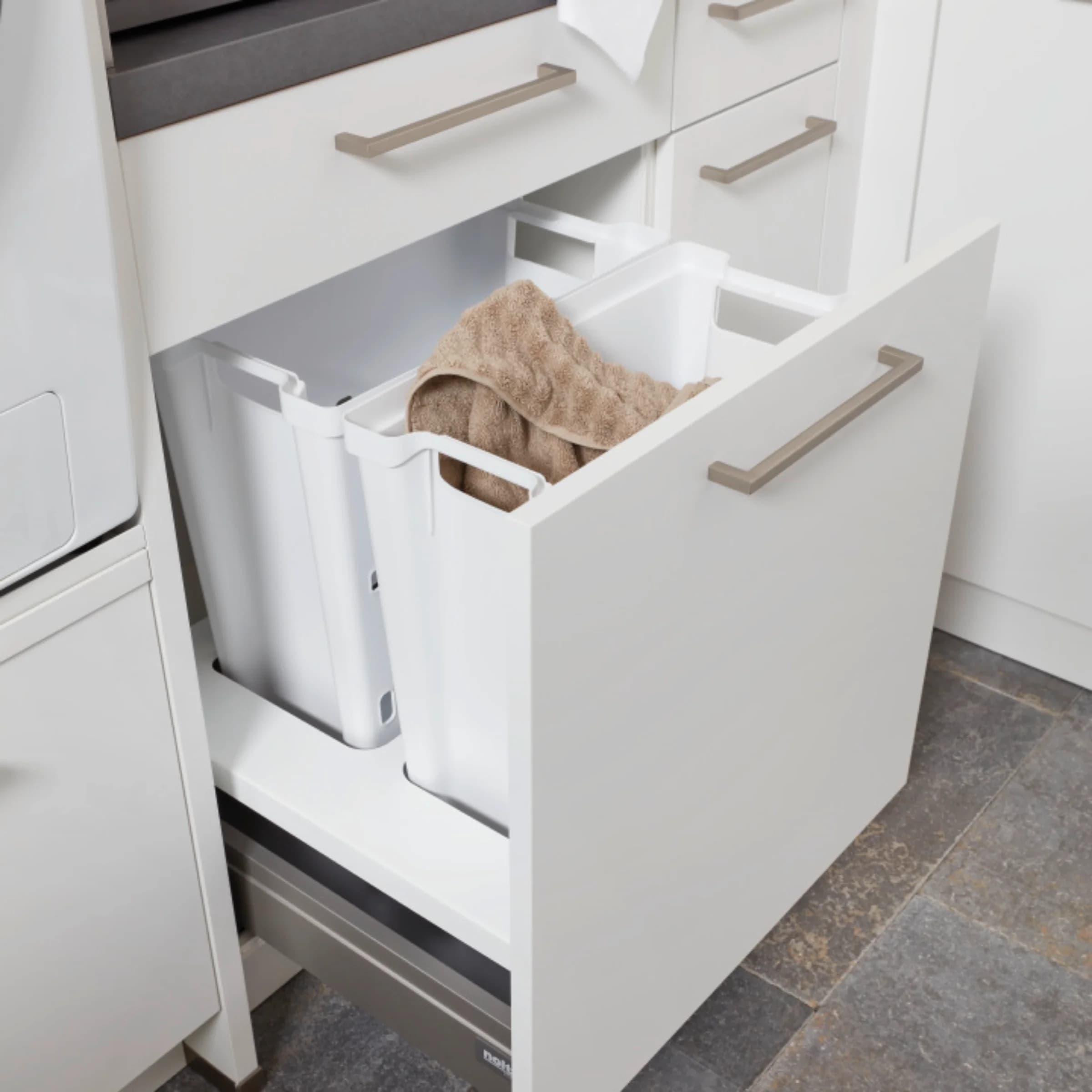 An open kitchen cabinet displaying containers with towels, typical of Nolte utility rooms.