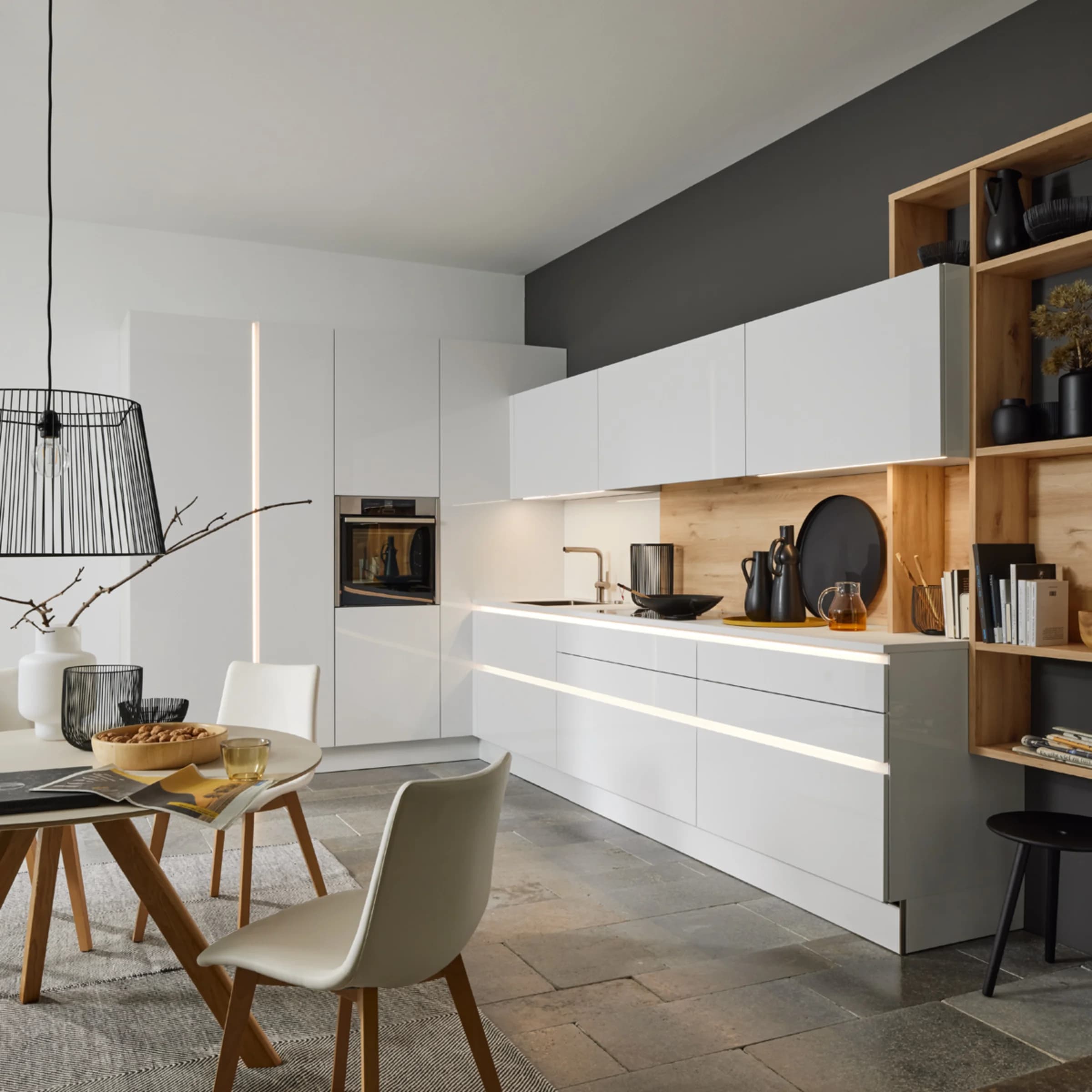 A modern kitchen with white cabinets and wood accents, designed by Nolte Kitchen.